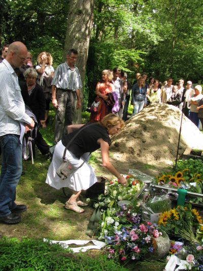 Marian schept zand over de kist